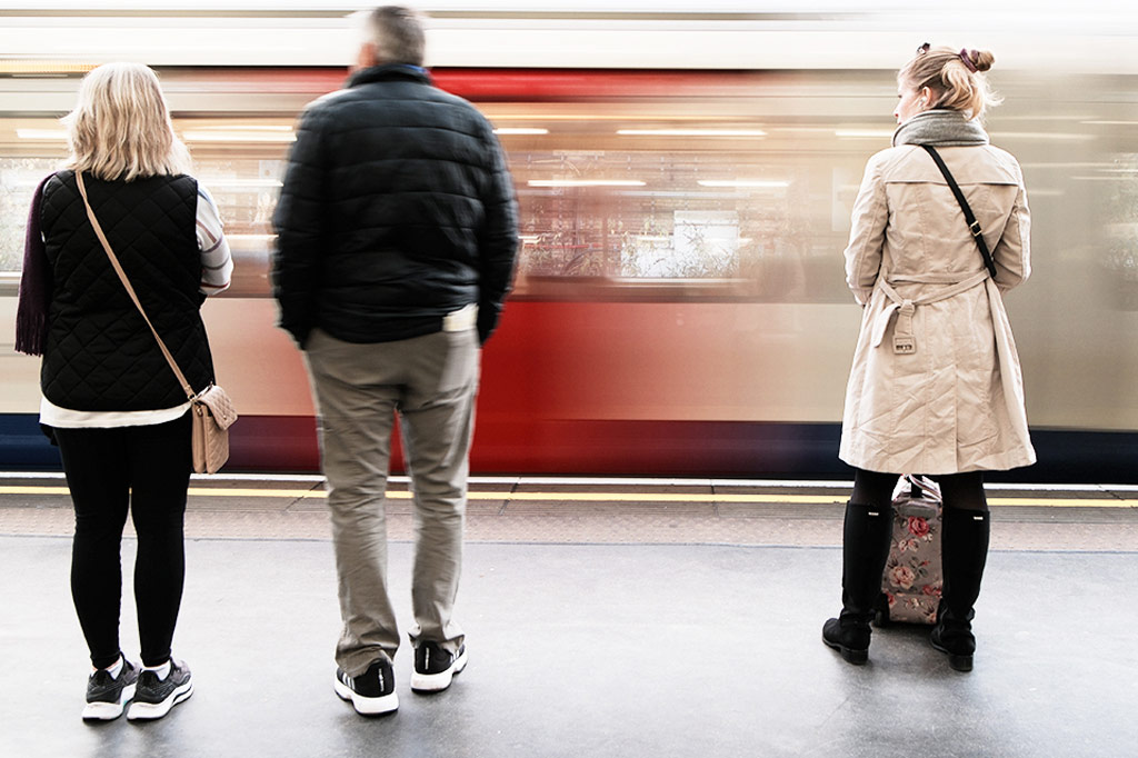 Long exposure, motion blurred shot of a tube train with three passengers waiting in the foreground